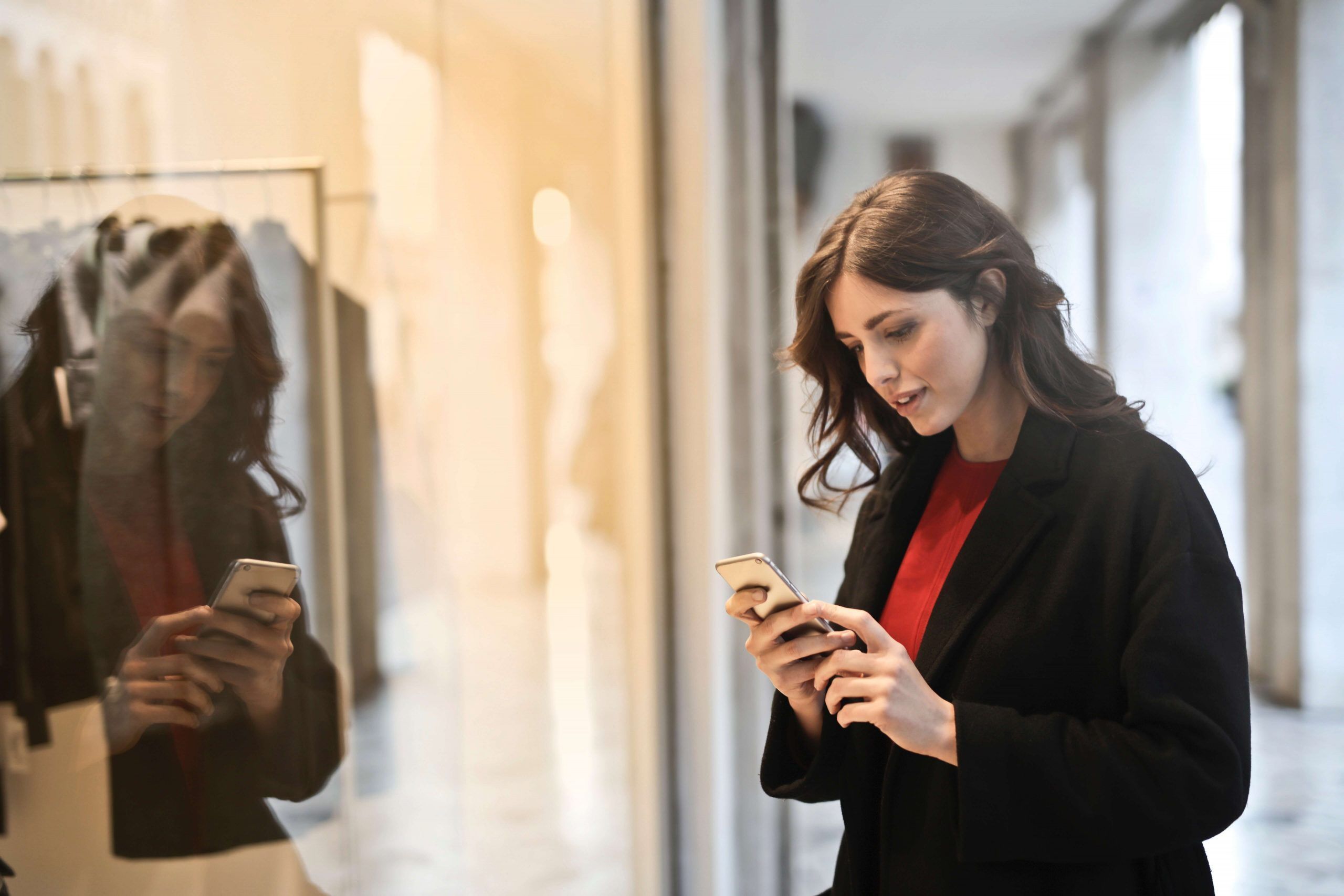 mujer mirando el movil entrando a una tienda abierta que no está en concurso de acreedores